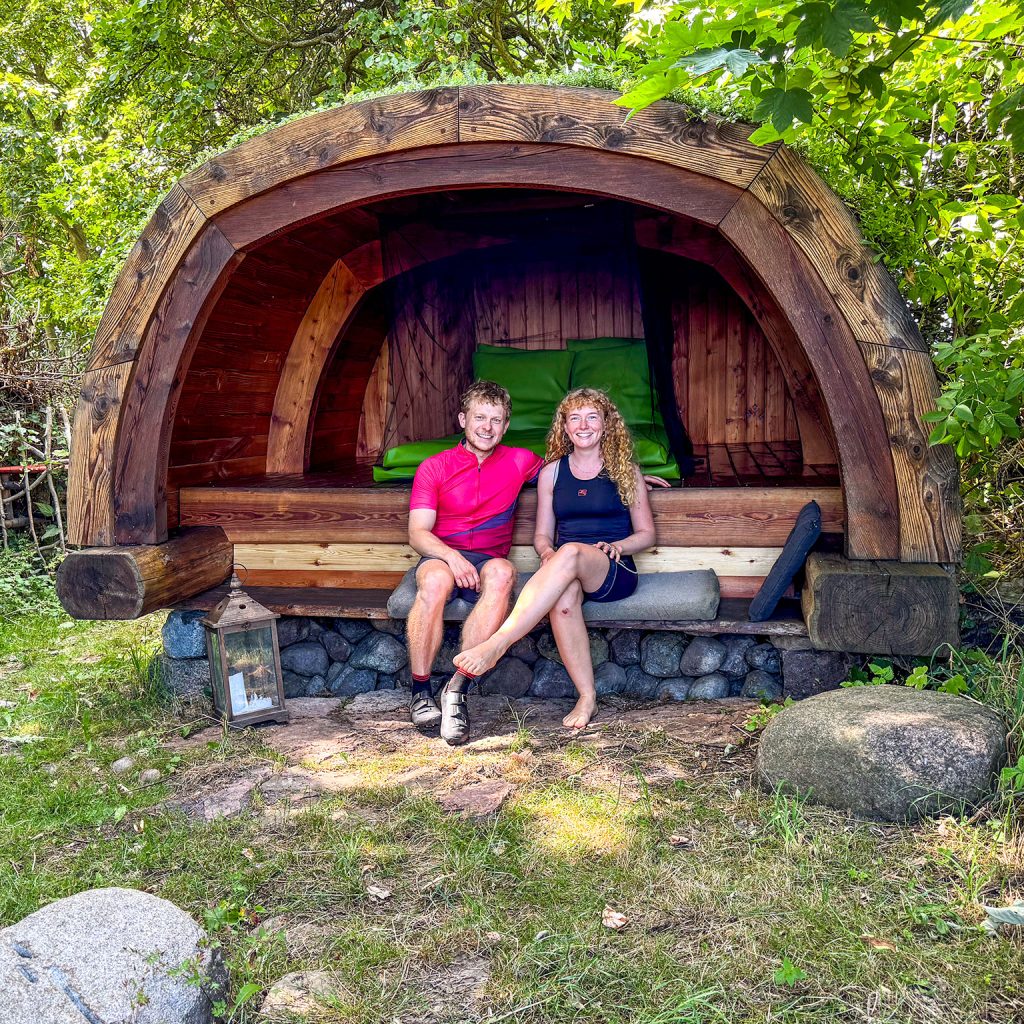 Zwei junge Touristen genießen die Shelter-Übernachtung in Sandvig mit Zugang zu Trinkwasser og Komposttoilette an der Radroute 9.